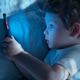 Child Lying in Bed staring intently at his smartphone Child Lying in Bed staring intently at his smartphone - PhotoDune Item for Sale