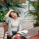 Asian businesswoman or student massaging neck across a laptop while sitting at table in garden cafe. Asian businesswoman or student massaging neck across a laptop while sitting at table in garden cafe. - PhotoDune Item for Sale