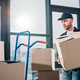 Delivery man stacking boxes on cart Stock Photo by LightFieldStudios