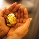 Hands holding a decorative golden egg filled with shiny coins Hands holding a decorative golden egg filled with shiny coins - PhotoDune Item for Sale