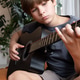 Young boy playing an acoustic guitar indoors, focused on pressing strings and fretboard Young boy playing an acoustic guitar indoors, focused on pressing strings and fretboard - PhotoDune Item for Sale
