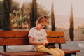 Teen girl sitting in park alone, holding gadget tablet pad in hands, smiling. Having videocall Teen girl sitting in park alone, holding gadget tablet pad in hands, smiling. Having videocall - PhotoDune Item for Sale