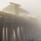 Surfer Walking Under the Pier in Morning Mist Surfer Walking Under the Pier in Morning Mist - PhotoDune Item for Sale