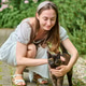 Young woman petting tortoiseshell cat outdoors on garden path Young woman petting tortoiseshell cat outdoors on garden path - PhotoDune Item for Sale