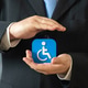 A businessman holds a symbol for people with disabilities. Support for people with limited mobility A businessman holds a symbol for people with disabilities. Support for people with limited mobility - PhotoDune Item for Sale