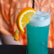Refreshing blue cocktail with woman in orange shirt background. Refreshing blue cocktail with woman in orange shirt background. - PhotoDune Item for Sale