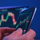 Close up, investor using smartphone for real-time stock market monitoring Close up, investor using smartphone for real-time stock market monitoring - PhotoDune Item for Sale