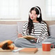 A beautiful young Asian woman in cozy clothes, wearing headphones, writes in her diary on the sofa. A beautiful young Asian woman in cozy clothes, wearing headphones, writes in her diary on the sofa. - PhotoDune Item for Sale