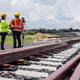 Two engineers in safety gear stand beside newly constructed railway tracks Two engineers in safety gear stand beside newly constructed railway tracks - PhotoDune Item for Sale
