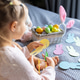Young girl cutting colorful paper bunnies on a bed next to a basket of eggs Young girl cutting colorful paper bunnies on a bed next to a basket of eggs - PhotoDune Item for Sale