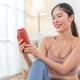 Joyful Asian woman holding beverage can at home Joyful Asian woman holding beverage can at home - PhotoDune Item for Sale