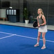 Female standing ready on blue court by glass wall in sportswear holding black paddle, copy space Female standing ready on blue court by glass wall in sportswear holding black paddle, copy space - PhotoDune Item for Sale