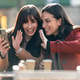 Two attractive friends enjoying coffee while doing a videocall with smartphone sitting on terrace Two attractive friends enjoying coffee while doing a videocall with smartphone sitting on terrace - PhotoDune Item for Sale