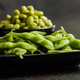 Green edamame pods. Fresh soybeans on plate on black table. Green edamame pods. Fresh soybeans on plate on black table. - PhotoDune Item for Sale