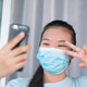 Portrait of a young attractive woman with face mask making selfie photo on smartphone. Portrait of a young attractive woman with face mask making selfie photo on smartphone. - PhotoDune Item for Sale