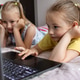 Two sisters 7-8 years old playing a game on a laptop lying on the bed in the room. Two sisters 7-8 years old playing a game on a laptop lying on the bed in the room. - PhotoDune Item for Sale