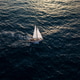 Aerial video of a white sailboat sailing alone on deep blue sea. Calm waves shimmer under sunlight. Aerial video of a white sailboat sailing alone on deep blue sea. Calm waves shimmer under sunlight. - PhotoDune Item for Sale