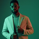 Stylish African man in modern chic attire posing against a green background, showcasing confidence Stylish African man in modern chic attire posing against a green background, showcasing confidence - PhotoDune Item for Sale