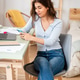 Smiling woman sitting at desk in home office. Smiling woman sitting at desk in home office. - PhotoDune Item for Sale