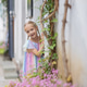 Smiling young girl with braided hair standing by a wall in a flower-lined street Smiling young girl with braided hair standing by a wall in a flower-lined street - PhotoDune Item for Sale