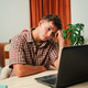 Frustrated young man struggling with issues while sitting at a desk in front of an open laptop Frustrated young man struggling with issues while sitting at a desk in front of an open laptop - PhotoDune Item for Sale