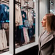 Woman admires clothing display in a shop window during evening hours Woman admires clothing display in a shop window during evening hours - PhotoDune Item for Sale