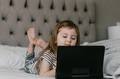 Toddler girl lies in bed, using tablet pad for watching cartoons, resting at home, neutral colors Toddler girl lies in bed, using tablet pad for watching cartoons, resting at home, neutral colors - PhotoDune Item for Sale