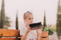 Little girl using gadget tablet pad. female sitting on bench , holding gadget thoughtful face Little girl using gadget tablet pad. female sitting on bench , holding gadget thoughtful face - PhotoDune Item for Sale