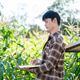 Asian farmer man in checkered shirt typing on laptop as standing in green corp farm under sunlight. Asian farmer man in checkered shirt typing on laptop as standing in green corp farm under sunlight. - PhotoDune Item for Sale
