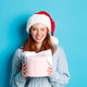 Winter holidays and Christmas Eve concept. Cute redhead girl in sweater and Santa hat, holding New Winter holidays and Christmas Eve concept. Cute redhead girl in sweater and Santa hat, holding New - PhotoDune Item for Sale