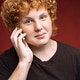 Portrait of smiling curly red-haired freckled teenager with telephone on red background Portrait of smiling curly red-haired freckled teenager with telephone on red background - PhotoDune Item for Sale
