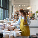 Woman in apron checking inventory of ceramic dishes in a retail store Woman in apron checking inventory of ceramic dishes in a retail store - PhotoDune Item for Sale