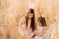 Two little girls sisters sitting in wheat field collecting red eggs in basket. Celebrating Easter Two little girls sisters sitting in wheat field collecting red eggs in basket. Celebrating Easter - PhotoDune Item for Sale
