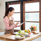 Happy woman holding tablet looking at recipe making a vegetable sandwich at kitchen cooking counter. Happy woman holding tablet looking at recipe making a vegetable sandwich at kitchen cooking counter. - PhotoDune Item for Sale