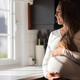 Smiling pregnant woman standing by a window in bright sunlight Smiling pregnant woman standing by a window in bright sunlight - PhotoDune Item for Sale