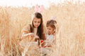 Two little girls sisters sitting in wheat field collecting red eggs in basket. Celebrating Easter Two little girls sisters sitting in wheat field collecting red eggs in basket. Celebrating Easter - PhotoDune Item for Sale