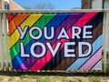 You are loved written on a progress pride flag integrated in one flag hanging on a fence You are loved written on a progress pride flag integrated in one flag hanging on a fence - PhotoDune Item for Sale