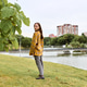 Young woman in yellow plaid jacket standing by riverbank with cityscape background Young woman in yellow plaid jacket standing by riverbank with cityscape background - PhotoDune Item for Sale