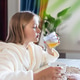 Young girl in bathrobe drinking orange juice at the kitchen table Young girl in bathrobe drinking orange juice at the kitchen table - PhotoDune Item for Sale