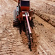 Construction equipment works on a dirt trench at a building site during daylight hours Construction equipment works on a dirt trench at a building site during daylight hours - PhotoDune Item for Sale