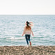 Back portrait of a girl in cozy sweater and jeans running on the winter beach to the sea. Woman Back portrait of a girl in cozy sweater and jeans running on the winter beach to the sea. Woman - PhotoDune Item for Sale