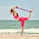 Adult woman practicing yoga with resistance band on sandy beach near ocean under clear sky Adult woman practicing yoga with resistance band on sandy beach near ocean under clear sky - PhotoDune Item for Sale