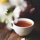 Cup of black tea and two chamomile flowers on wooden surface Cup of black tea and two chamomile flowers on wooden surface - PhotoDune Item for Sale