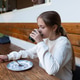 Young girl drinking from a glass at an outdoor wooden table Young girl drinking from a glass at an outdoor wooden table - PhotoDune Item for Sale