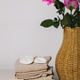 On the table lies a stack of baby clothes with a wicker vase and roses. On the table lies a stack of baby clothes with a wicker vase and roses. - PhotoDune Item for Sale