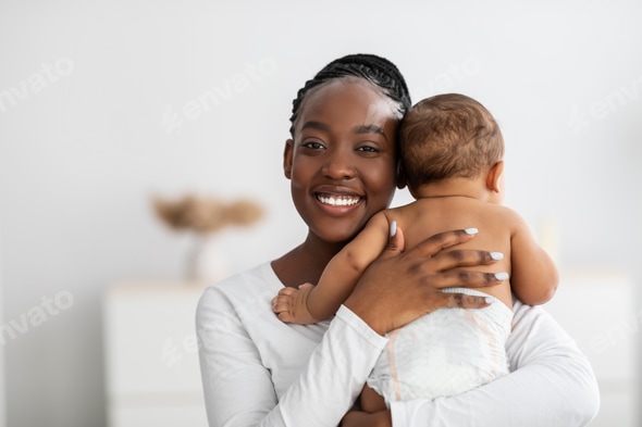 Happy African American mom hugging her cute infant Stock Photo by