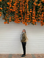 Woman looking up at plentiful cascading orange flower vines tumbling over a white wall pops of color Woman looking up at plentiful cascading orange flower vines tumbling over a white wall pops of color - PhotoDune Item for Sale
