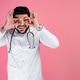 Handsome male doctor wearing medical gown, looking at camera, smiling, touching eyes. Handsome male doctor wearing medical gown, looking at camera, smiling, touching eyes. - PhotoDune Item for Sale