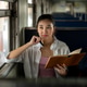 Pretty asian woman holding pen look away from book as sitting on bench in carriage at train station. Pretty asian woman holding pen look away from book as sitting on bench in carriage at train station. - PhotoDune Item for Sale