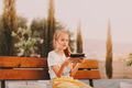 Teen girl sitting in park alone, holding gadget tablet pad in hands, looking away. Golden hour light Teen girl sitting in park alone, holding gadget tablet pad in hands, looking away. Golden hour light - PhotoDune Item for Sale